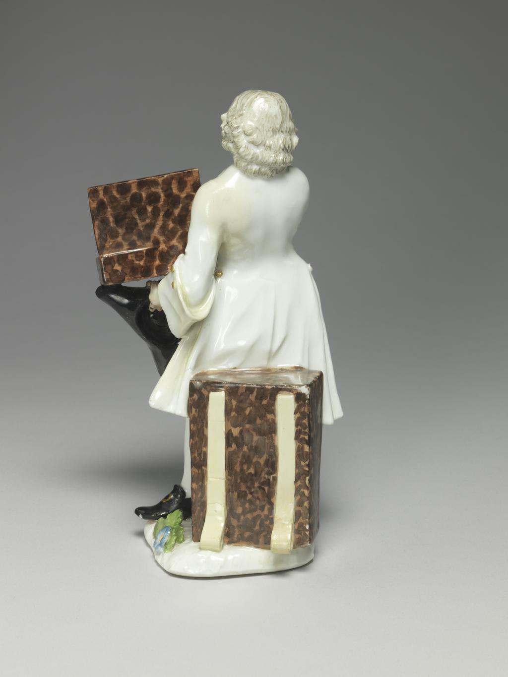 An image of A knife seller. Meissen Porcelain Manufactory. Kaendler, Johann Joachim, modeller, derived from (German, 1706-1775). Reinicke, Peter, modeller, derived from (German, 1715-1768). Hard-paste porcelain, press-moulded, and painted overglaze in enamels, and gilt. The flat underside is unglazed and has a small circular ventilation hole near the back. Height, whole, 18.7 cm, width, whole, 10 cm, depth, whole, 9 cm, circa 1745-1750. Production Note: This figure is Meissen model no. 965 which was modelled after 'Des Couteaux, des Cizeaux, des Peignes', the third print of the fourth set of prints entitled 'Études prises dans le bas Peuple ou les Cris de Paris' engraved by the comte de Caylus (1692-1765) after drawings by Edmé Bouchardon (1689-1762), and published in 1742. The figure's stance is transposed from the engraving.