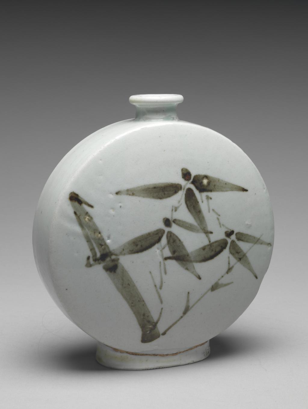 An image of Flattened flask with bamboo design. Unknown pottery, Songjong-ri kilns. This typical seventeenth-century flask has a flattened moon-shaped body, narrow waisted neck and broad oval foot that was separately made and joined to the body. Each side is painted in underglaze iron-oxide with short stems of bamboo in shaded tones of brown. The glaze is tinged with blue. The footring shows traces of fine sand from the firing support. Porcelain, moulded, luted, painted in iron-brown, and glazed, height 20.1 cm, diameter, rim, 3.7 cm, diameter, foot, 8.8 cm, circa 1630-1660. Choson Dynasty. Production Note: Such flasks were probably used at outings and picnics. This one was probably made in the kilns at Sondong-ri which were active from 1640 to 1649, or at Songjong-ri, around 1650.