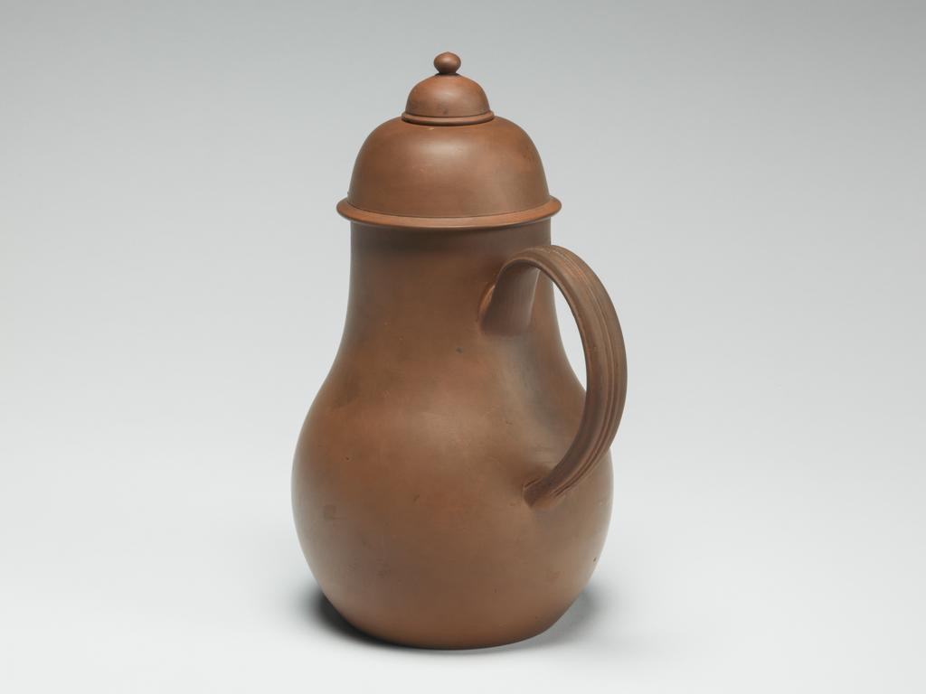An image of Chocolate Pot. Unknown Staffordshire factory. Pear shaped body with projecting lip, and reeded loop handle, the domed lid having a smaller second lid fitting into an opening in the top. On the base, an imitation Chinese seal mark. Red dry-bodied stoneware, thrown and turned, height, whole, 21.5 cm, circa 1760.