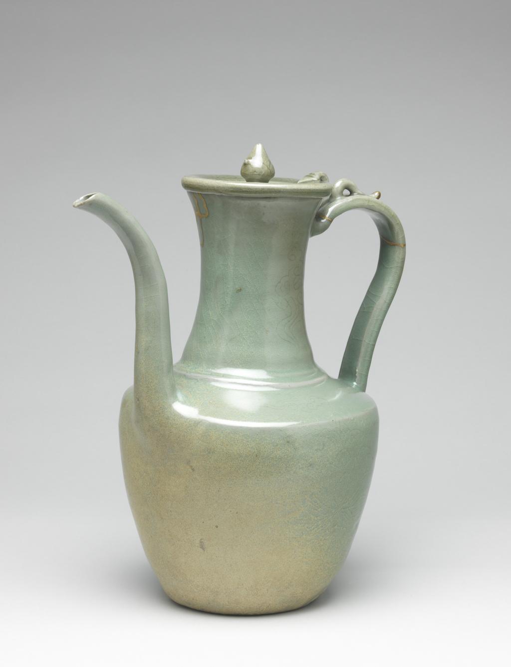 An image of Ewer and cover with lotus and cloud designs. Unknown pottery. Possibly North Cholla province, Puan-gun, Yuch'on-ri kilns, or South Cholla province, Kangjin-gun, Sadang-ri kilns, Korea. This ewer has a tall waisted neck with a raised ridge where it meets the angled shoulder. The spout is very long, the strap-shaped handle is attached at the shoulder and continues almost down to the base. The footring is low. The flat dish-shaped cover has a lotus-bud knob and a small loop at the rim corresponding to a loop on top of the handle. The body is incised with a large lotus flower on either side and a border of lotus petals at the base, while the shoulder and neck feature cloud motifs spaciously arranged. The glaze is of pale blue-green colour, clear and glossy, and somewhat discoloured at the top of the neck. The footring has been wiped free of glaze and shows traces of fire-clay spurs. Stoneware, thrown, with parts attached, incised and celadon-glazed. Height, whole, 29.5 cm, diameter, rim, 8.7 cm, diameter, foot, 9.7 cm, circa 1100-1200. Koryo Dynasty.