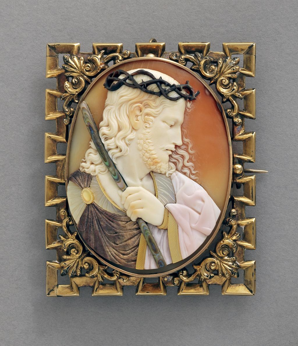 An image of Jewellery. Brooch/Pendant. Lamant, France. Set with an oval comesso cameo of Christ crowned with thorns, his head in profile to the right, his left hand, grasping a rod, resting on his chest. Rectangular with crenellated edge and an applied anthemion flanked by scrolls in each corner. Pin-fastening across the back and a loop for suspension at the top. Gold, shell, height 6.5 cm, width 5.5 cm, circa 1850.