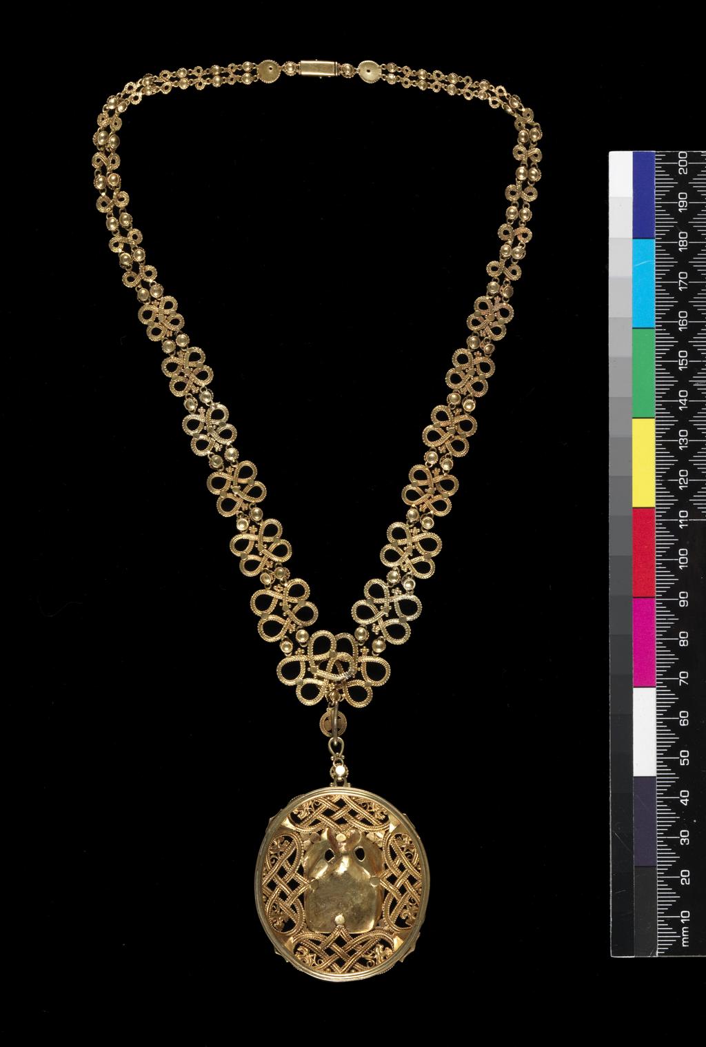 An image of Jewellery. Pendant and chain. Wilson, Henry (British, 1864-1934). The almost circular pendant centred on an angel holding a dove, surrounded by four openwork knots, leaves and berries. The loop for suspension is decorated with a larger circular berry. The chain is composed of openwork figure-of-eight knots of graduated size, separated by pairs of circular berries. On either side of the fastening there is a circular stud. Gold, height, pendant, 6.1 cm, width, pendant, 4.4 cm, length, chain, 42.7 cm, circa 1900-1910. Acquisition Credit: Given by Mrs J. Hull Grundy.