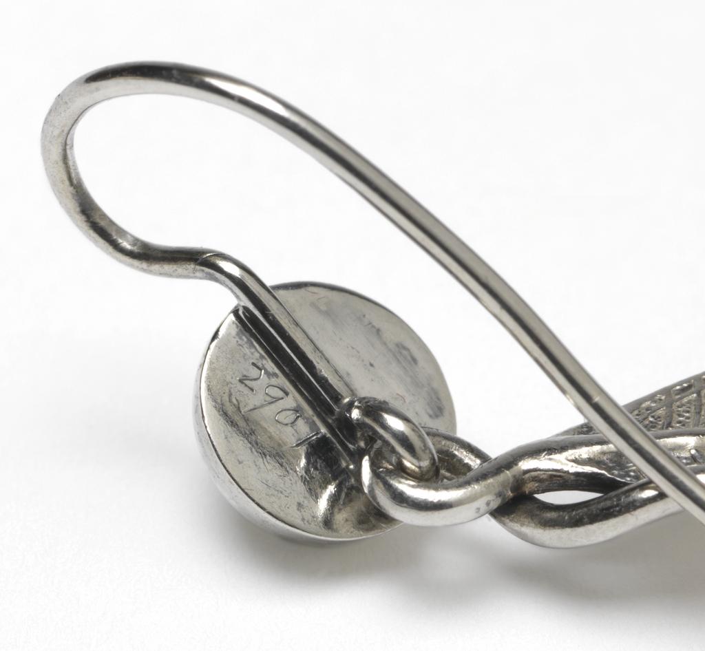 An image of Jewellery. Pendant & earrings. Phillips Brothers, London. The pendant composed of three cast laurel leaves and a berry, the stems of which are coiled to form a wide loop for suspension. Each earring is cast in the shape of a laurel leaf, the stem twisted over to form a loop into which is hooked a hemispherical berry, the stem of which is curved over and downwards to pass through a pierced ear. In original D-shaped maroon morocco case, the base lined with dark red velvet, the lid with purple silk, printed in gold below a crown 'PHILLIPS,/23, COCKSPUR ST/LONDON.' On the base of the case, a rectangular label, printed 'FENTON/33 Cranbourn St,/London' with a row of figures above in blue-black ink '3970 . . . . ' that of a later vendor. Silver, height, pendant, 8.8 cm, height, earrings, 7.2 cm, circa 1860. Victorian. Acquisition Credit: Given by Mrs J. Hull Grundy.