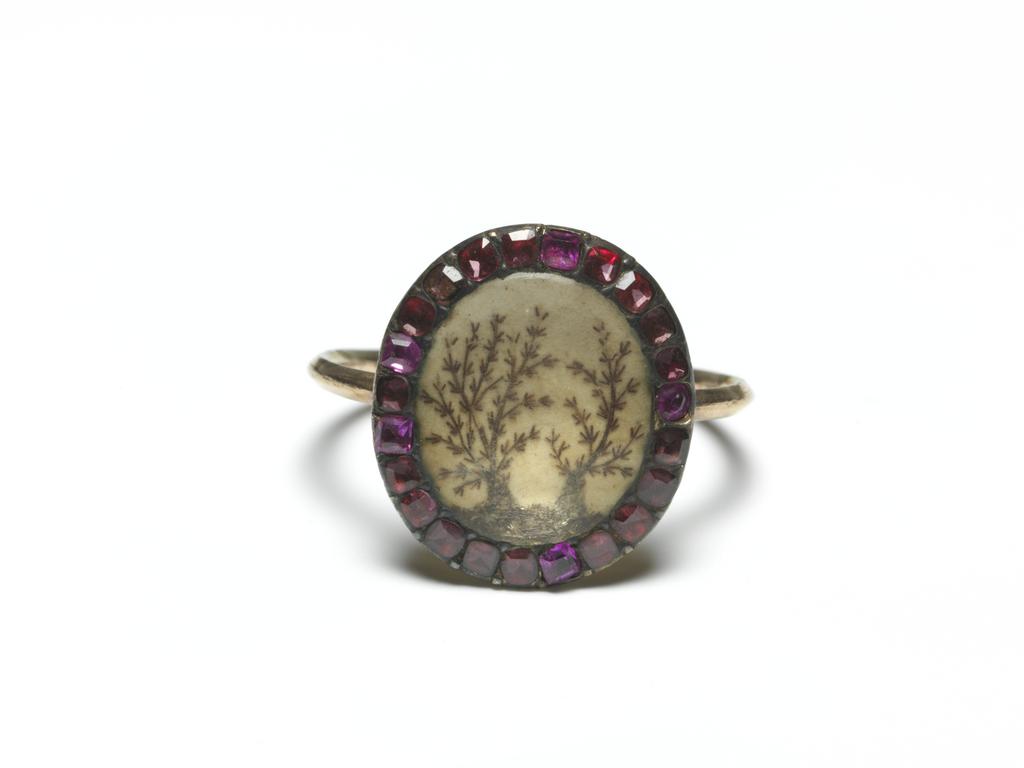 An image of Jewellery/Mourning Ring.  Gold hoop, triangular in section. Oval bezel surrounded by small square faceted garnets, with central design, covered with glass of two (rosemary?) bushes executed in hair. On the back of the bezel is inscribed: 'Miss Judith Stubbs Ob: 29 July 1769 Aet 50'. Height, hoop, 1.5 mm, length, hoop, 20.0 mm, height, bezel (oval) 4.0, mm, width, bezel (oval) 13.5 mm, length, bezel (oval) 15.5 mm, 1769. English.