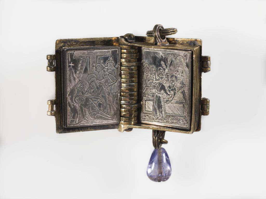 An image of Pendant Book. Jewellery/Pendant. Silver-gilt, with leaves made of silver and engraved with scenes from the Passion. Perhaps for attaching to a rosary, with pendant amethyst. Scenes: Annunciation, Nativity, Last Supper, Agony in the Garden, Kiss of Judas, Christ before Pilate, Scourying of Christ, The Mocking of Christ, Christ Carrying the Cross, the Erection of the Cross, Christ being Nailed to the Cross, the Crucifixion Deposition, Entombment, Resurrection, Christ Child Enthroned, a Pope and a female Saint. Silver-gilt, height, whole, 6.0 cm, width, whole, 2.8 cm, circa 1500- circa 1700. German.