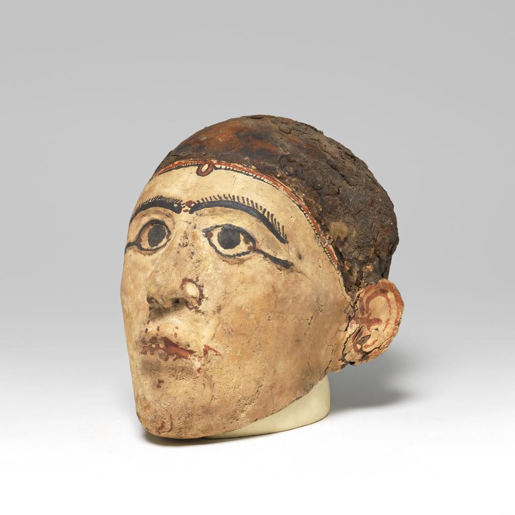 An image of Mummy trappings. Mummy mask, moulded on male skull. Production Place/Find Spot: Egypt. Depth 0.12 m, height 0.23 m, length 0.1475 m.