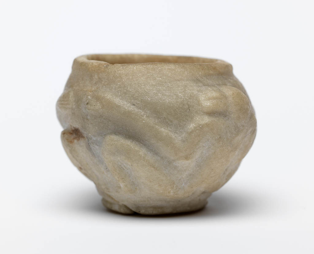An image of Stone vessel. Calcite vessel with monkeys. Jar, squat, with two monkeys on outside in relief. Used as an eye-paint jar. Production Place/Find Spot:: Egypt. Calcite, carved, height 2.2 cm, 1976-1794 B.C. Dynasty 12.
