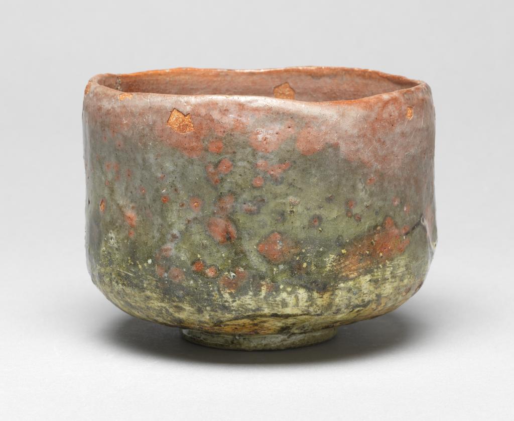 An image of Japanese pottery. Tea Bowl. Unknown pottery, Japan, Kyoto. Footed cylindrical tea bowl with bright orange-red body. Underglaze decoration of seven cranes in a green and white landscape, the whole covered with a clear glaze which has degraded. The foot and the base of the bowl appear to be covered with a clear varnish. Earthenware, hand built with clear underglaze, brush painting decoration, height 8.70 cm, diameter, rim, 11.90 cm, largest, diameter, bowl, 12.00 cm, diameter, foot, 5.50 cm, circa 1775-circa 1825. Edo period (1615-1868) / Meiji period (1868-1912).