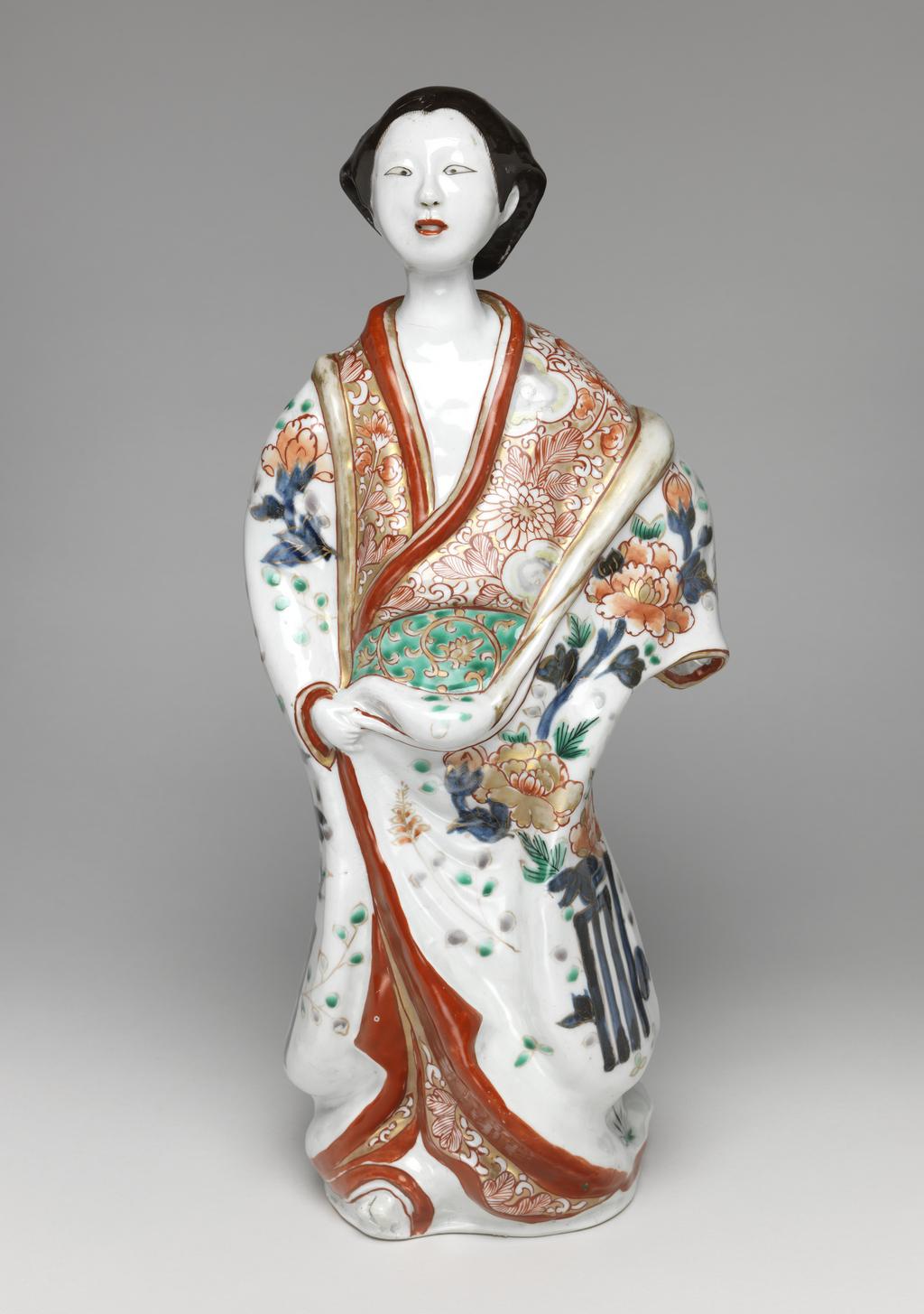 An image of Figure of a female Geisha. Japanese. Imari. Decorated in red, green, blue and black enamels. 1710-1770. Edo Period (1615-1868). Acquisition Credit: Given by David Hyatt King, through The Art Fund.