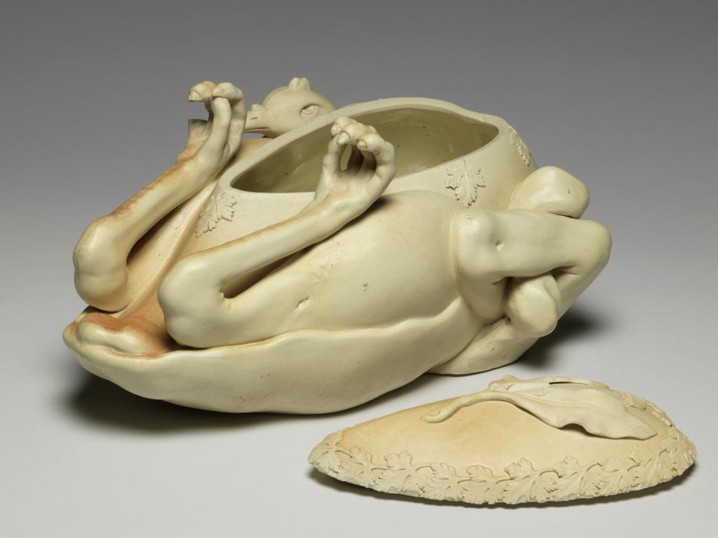 An image of Tureen and cover. ‘Pastry turkey’ tureen. John and William Turner, pottery, Staffordshire, Longton, Lane End. Moulded in the shape of a trussed and roasted fowl or game bird, breast upwards, with upturned feet and head tucked under one wing and egg-shaped cover fitting into breast. There is a relief moulded parsley garnish around the junction of the cover and body, and three moulded bay leaves which form a handle for the cover. Faint reddish-brown staining suggests roasting on parts of the upper surface. The interior is glazed. The underside is very slightly concave, with a narrow foot-rim. Cream stoneware, moulded, modelled and decorated with applied reliefs, height, whole, 15.5 cm, approx, length, whole, 33.6 cm, width, whole, 20.0 cm, approx, circa 1800. Production Note: Not dated, but social circumstances at this time indicate c.1800 the most likely date. Other examples dated c.1780-c.1820.