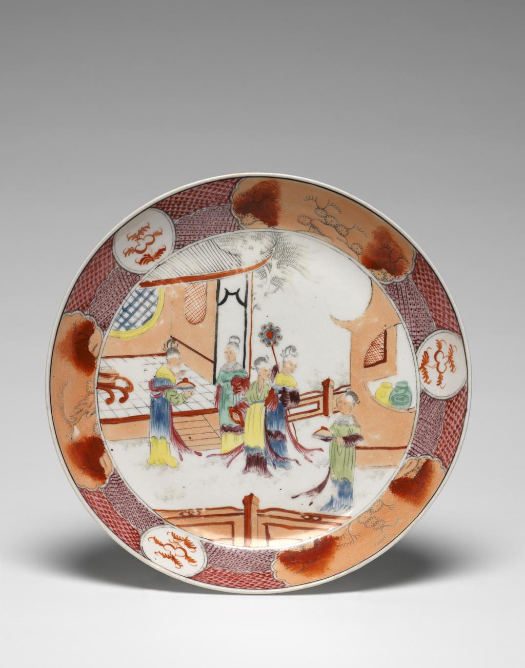 An image of Plate. New Hall Porcelain Factory, Staffordshire. Circular with shallow curved sides, standing on a footring. The centre is decorated with four ladies standing in front of a house or garden pavilion, and another further to the right stands in front of another building in which two jars are standing beside a circular opening. In the foreground thee is a fence. Round the edge there is a border of puce and pink, and purple and pink trellis patterns broken by three large shaped oblong panels enclosing red and black plants on an apricot ground, and three small circular panels with a red plant on a white ground. A black line runs round the rim. Pattern 621. Hybrid hard-paste porcelain, transfer-printed overglaze in black and painted in enamels, height, whole, 3.8 cm, diameter, whole, 20.4 cm, circa 1800. Chinese Style.