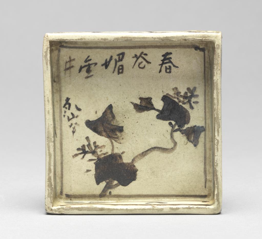 An image of Japanese pottery. Small plate for food. Kenzan, pottery studio, Japan, Kyoto. A square plate, small and shallow. Underglaze brushwork of pine in black, together with inscriptions in Chinese characters. Cloud decorations around the outside. Maker's mark and inscriptions in Chinese; on the plate; brushed; five Chinese characters poem and the signature KENZAN painted on the plate; five Chinese characters poem read ' the charming spring ivy blooming all over the valley' painted by KENZAN. Stoneware, hand-built, brush painting in black pigment, height 2.00 cm, width of the square, whole, 9.50 cm, larger, circa 1700-circa 1799. Edo Period (1615-1868). Production Note: this piece belongs to the three-piece set (C.183A, B & C-1934).