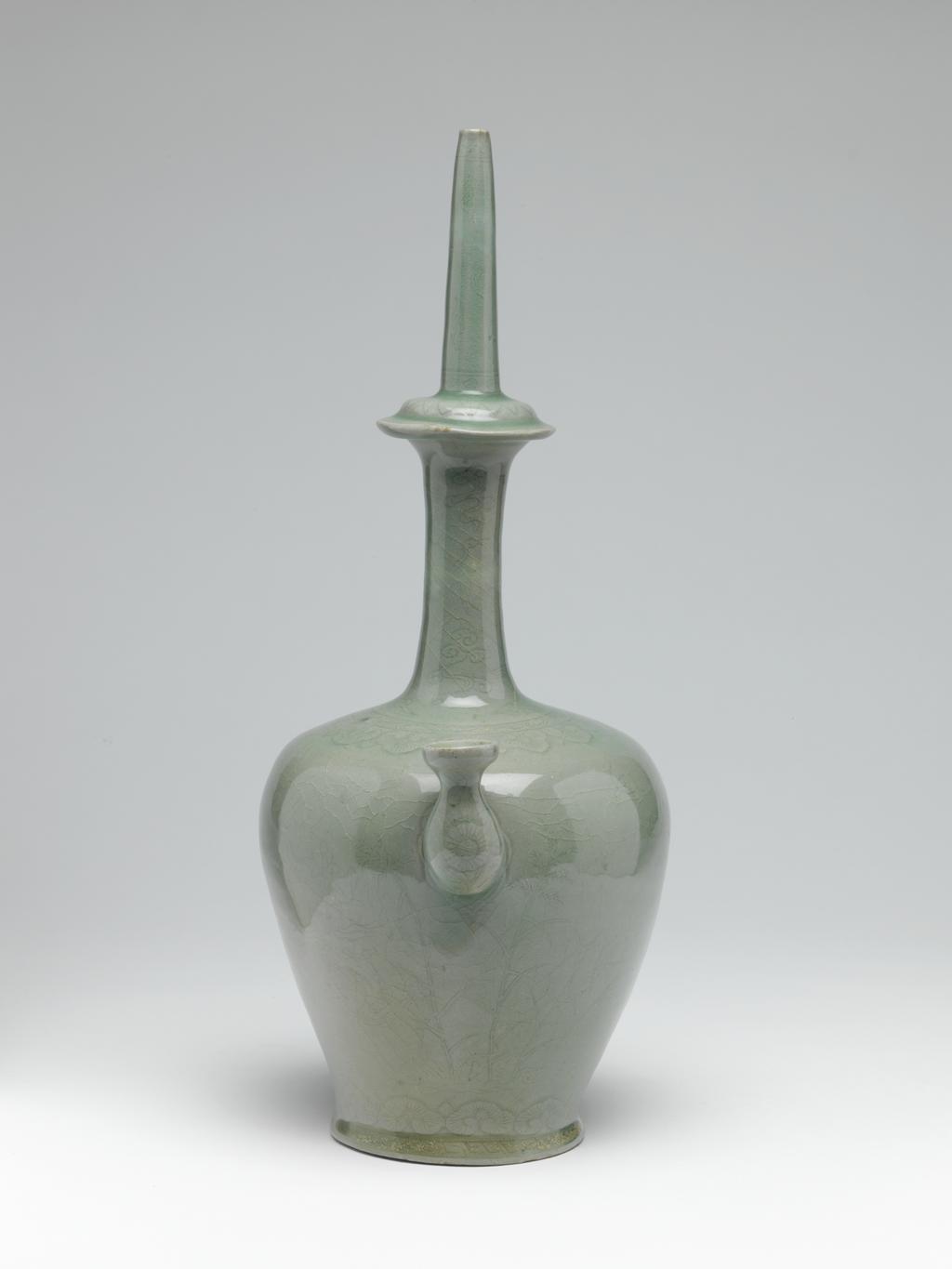 An image of Chongbyong. Kundika with willow and waterfowl design. This vessel has an ovoid body with a small spout on one side, and a long neck, with a flanged swelling in the centre. The lower part of the body contracts to a splayed footring, giving it a stable shape. The upper part of the long neck is cut into octagonal form, and has incised cloud motifs on each facet, while the projecting ring shows lotus petals and scrolling foliage. The lower part of the neck is decorated with flying cranes among clouds. A classic-scroll border and youi-heads are finely incised round the shoulder, and a key-fret border and further youi-heads round the foot. The body itself shows willow trees on one side and reeds on the other, with ducks and lotuses, flying cranes and geese delicately engraved between. Production Notes: This type of kundika, which is modelled on bronze examples decorated with silver inlay, was very popular in the Koryo dynasty. Both shape and design are very similar to the metal counterparts. The kundika (Chongbyong) was used in Buddhist ceremonies as a container for water, which was filled in through the spout and sprinkled from the narrow mouth. Similar sherds were excavated at kiln no.7, Sadang-ri, Kangjin-gun, South Cholla province, and were produced in the mature period of Koryo celadon, in the first half of the twelfth century. Production Place: Sadang-ri kilns. Kangjin-gun. South Cholla province. Korean. Stoneware, thrown, with applied lugs, incised and celadon-glazed, height (whole) 34.7 cm, diameter (maximum) 16.0 cm, diameter (foot) 9.0 cm, circa 1101 to 1150. Koryo Dynasty.