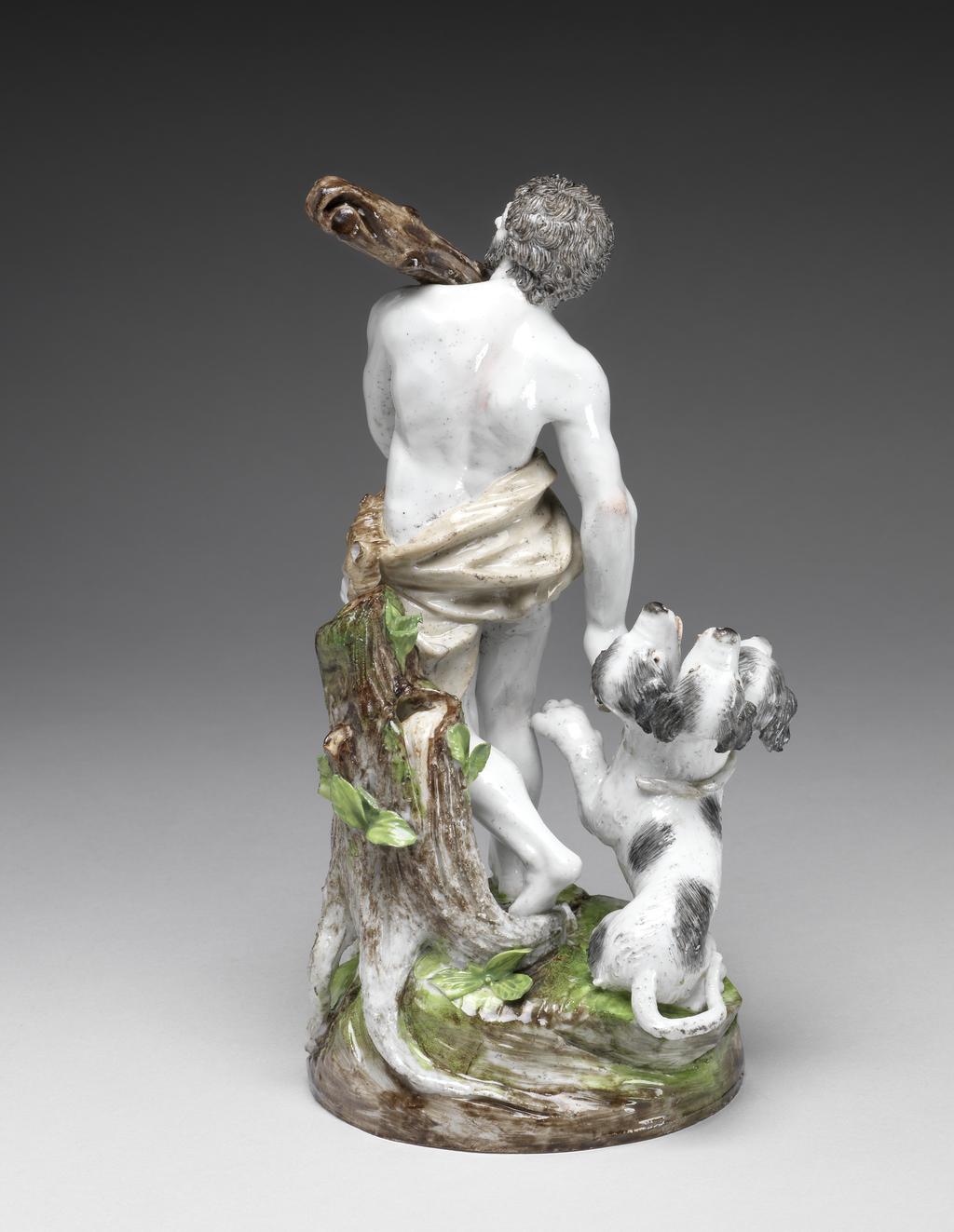 An image of Figure Group. Hercules and Cerberus. Le Nove Porcelain Factory, The Veneto, Le Nove. A brown lion skin and mask is draped around his hips. In his left hand he holds the lower end of a large dappled brown club which rests on his left shoulder. He holds a knotted rope in his right hand which is extended downwards. Cerberus, in the form of a friendly-looking black and white dog with three open-mouthed heads, is seated beside him. His left front paw is raised towards Hercules, and his tail is curled round and extends beyond the edge of the base. On his neck there is the remains of a rope which originally joined up with the knot held in Hercules’s hand. Hard-paste porcelain, press moulded and glazed, painted in polychrome enamels, height, whole, 21.9 cm, width, whole, 11.8 cm, width, base, 10.5 cm, circa 1785-1795. Antonibon-Parolin period.