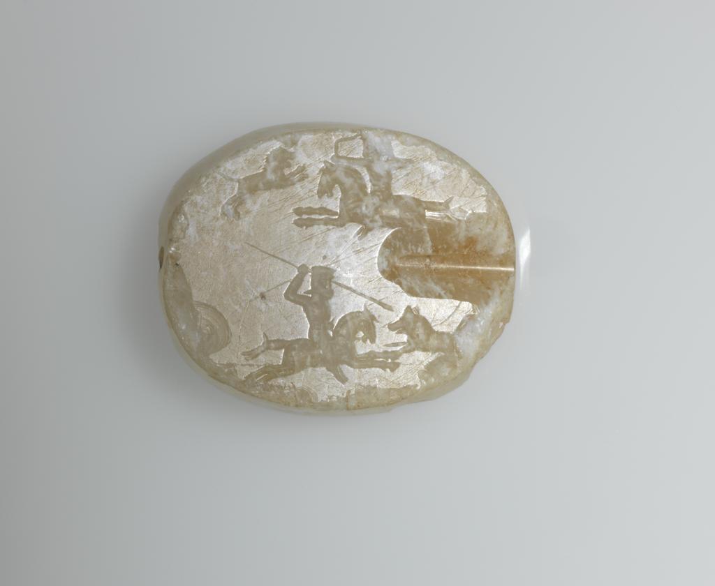 An image of Scaraboid Seal/Stamp Seal. Incised with hunting scene in which a horseman, facing right, discharges an arrow at a lion. Below, a second horseman, facing left, spears a wild boar. Chalcedony, cloudy, depth 0.025 m, length 0.012 m, width 0.031 m, 500-301 B.C. Graeco-Persian.