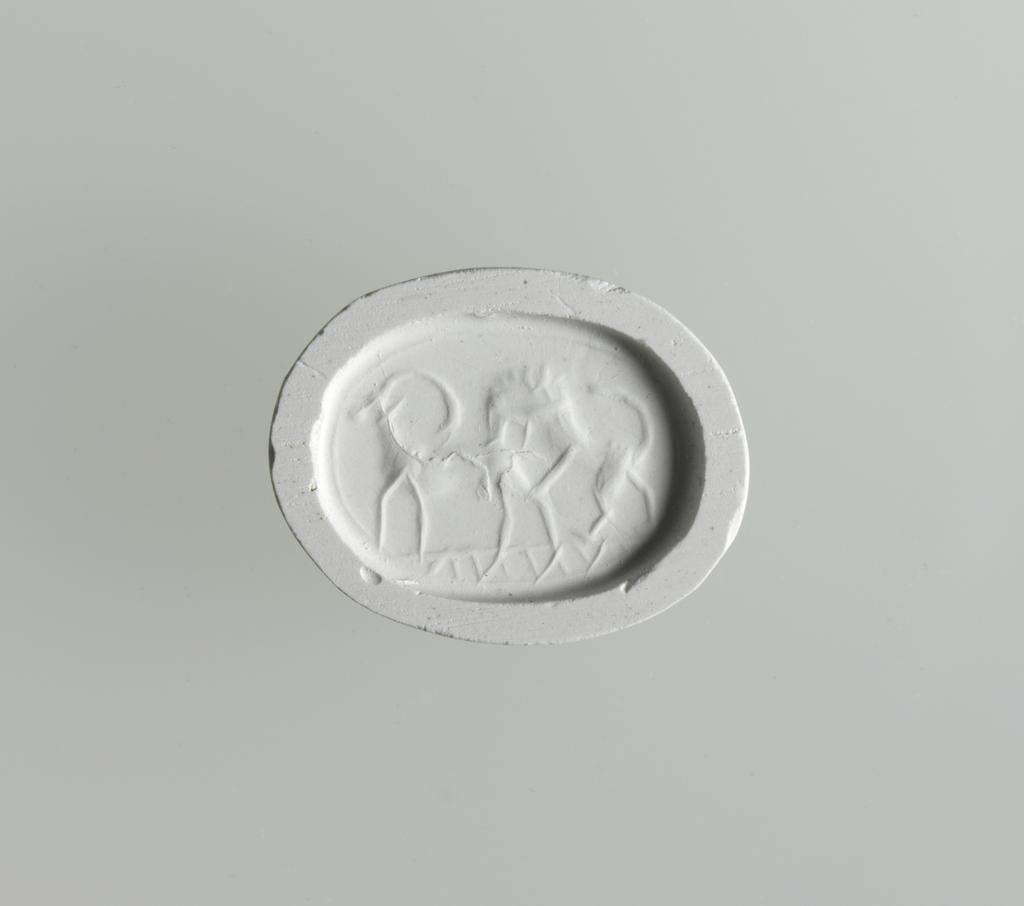 An image of Engraved gems/Scarab/Intaglio Cutting. Lion, leaping onto back of goat/ibex, in profile to left. Green steatite, height 15 mm, width 11.5 mm, depth 7.5 mm, circa 600-501 B.C. Phoenician, Greek influence.