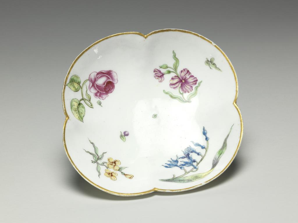 An image of Cup and saucer/ Teaware/ Goblet ou tasse à quatre pans rond. Vincennes Porcelain Manufactory. Of four-lobed form, painted in enamels with sprays of flowers and foliage, and gilded. Soft-paste porcelain, moulded, and painted overglaze (lead-glazed) in enamels, and gilding, height, cup, 4.8 cm, length, cup including handle, 10 cm, width, cup, 7.8 cm, height, saucer, 3 cm, length, saucer, 14.1 cm, width, saucer, 13.2 cm, circa 1749- circa 1752. Rococo.
