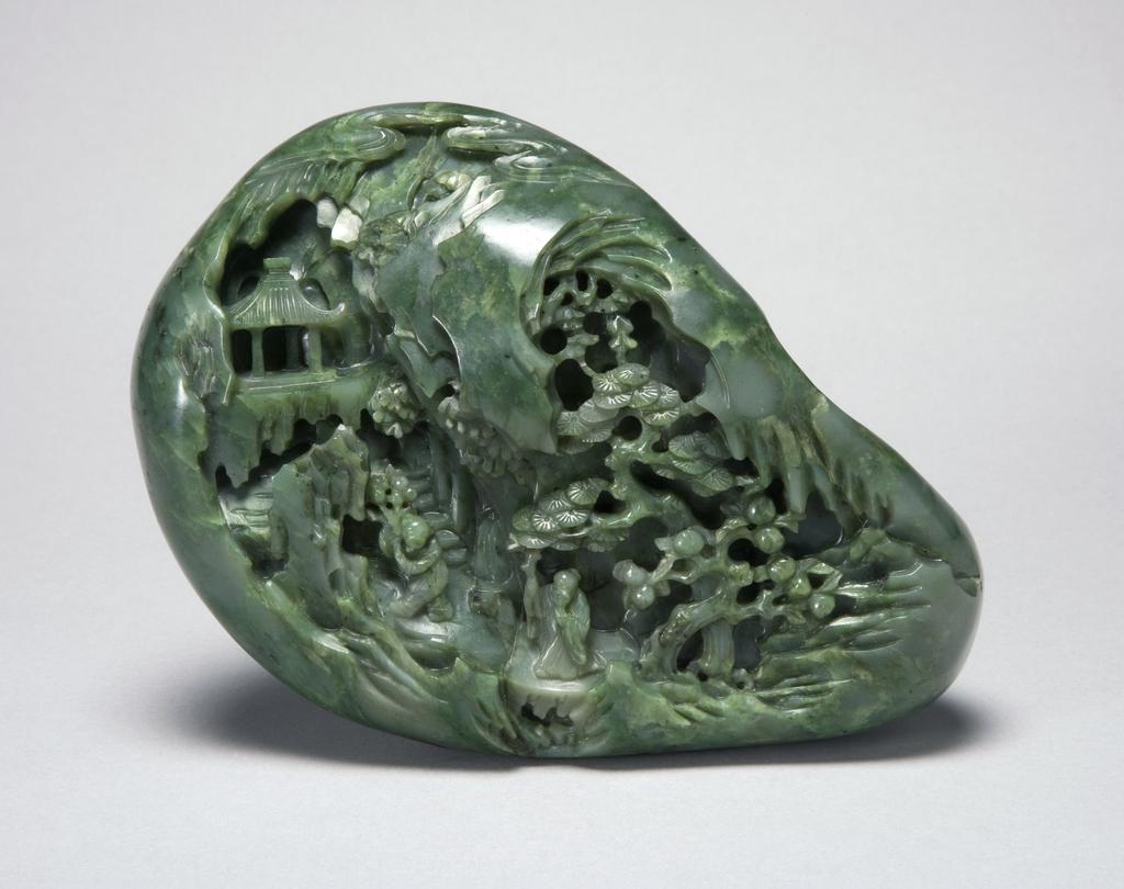 An image of Ornament/Boulder. Rich dark translucent green jade boulder carved with an old man with a stick and a boy with a branch of peach fruit in a landscape where peach and pine trees grow and a pavilion in the distance. The pine, peach and old man all represent longevity. The whole scene, together with a boy with a branch of peach in his hand can be interpreted as searching for immortality. The design may have been inspired by a woodblock print. Jade/nephrite, height 12.2 cm, length 15.8 cm, 1700-1800. Chinese.