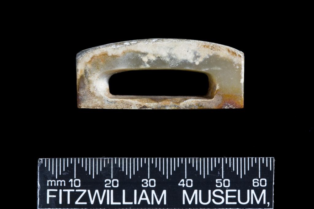 An image of Scabbard Slide/Sword fitting. Translucent pale green jade with extensively altered surface. The top is divided into two longitudinal sections, no decoration. Nephrite, height 1.85 cm, length 4.4 cm, width 2.5 cm, 200-1 B.C. Chinese.