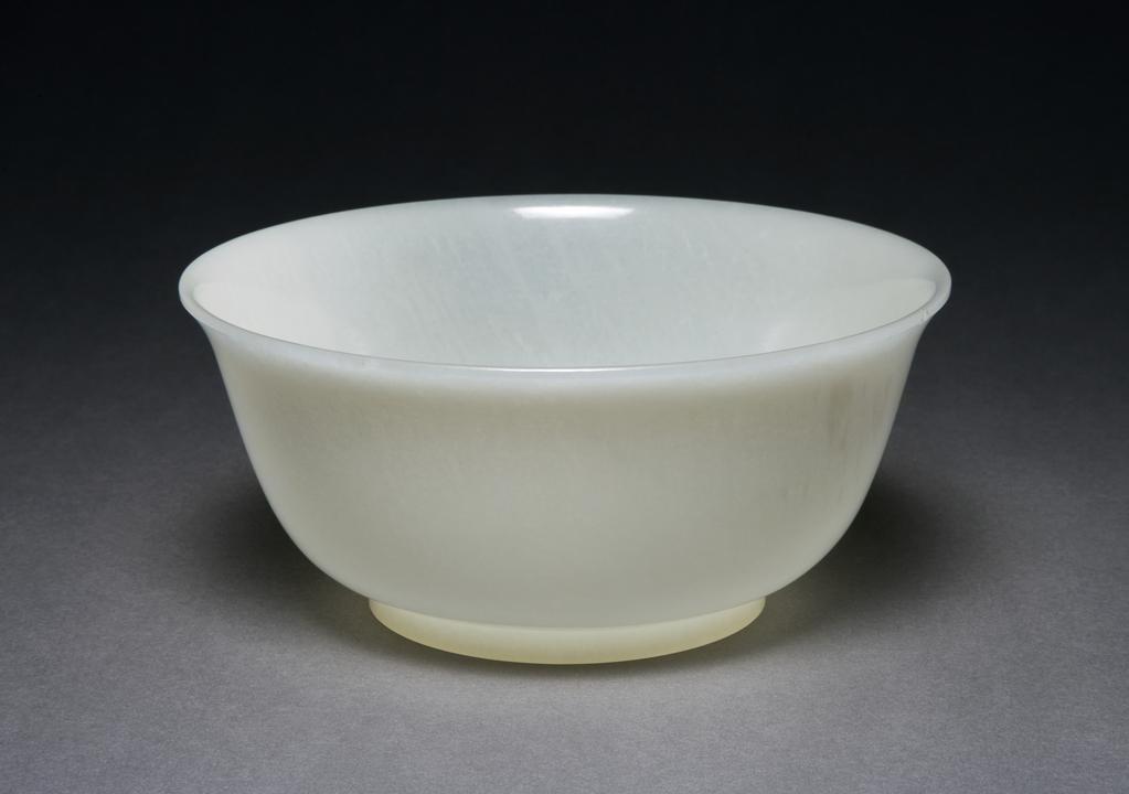 An image of One of a pair of translucent jade bowls of milky white colour. Each of deep round form rising from a neatly finished straight footring. Although the bowls are unmarked, the quality of the jade, their shape and highly polished surfaces, as well as the surviving label with these bowls, indicate that they may have formed part of the imperial collection during Emperor Qianlong’s reign. Height 7.4 cm, diameter 16 cm, 1736-1795 AD. See object record O.79 A & B-1946.
