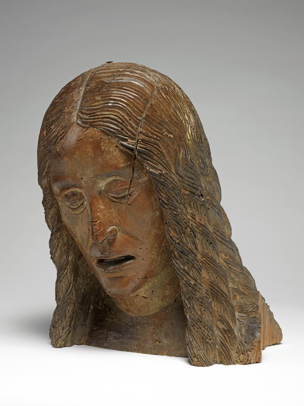 An image of Sculpture. Head of St John the Baptist (?). The head is bent forward, the hair hanging in long ringlets. The face is drawn and grief stricken with the lips parted; the nose is thin and aquiline. Italian lime wood, with traces of original polychrome, height 12 in, width 10 in, depth 8 in, c. 1470-1500. Production Place: Italy.