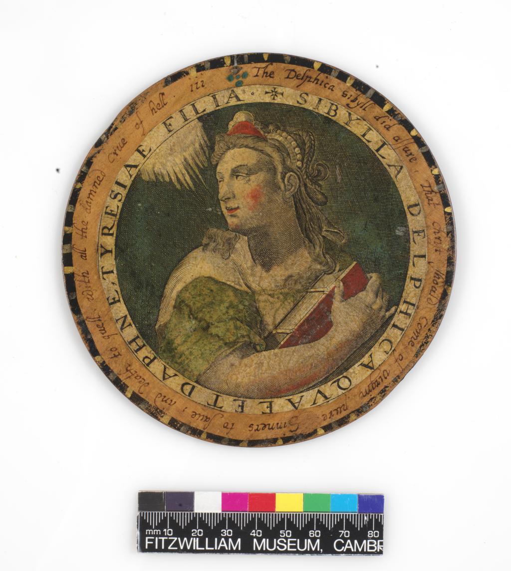 An image of Roundel or trencher. One of twelve wooden roundels, with an applied print of the Delphic Sibyl. Hand-coloured in red, green, ochre and black. Inscribed in black ink. Undecorated reverse. With a small hole near the top at the edge, diameter 13.7 cm, circa 1601-1625. Part of M.5.1-13 & A-1920: Box containing twelve roundels or trenchers. Unknown maker, after Passe, Crispijn I de, printmaker (Flemish, 1564-1637). Circular box and cover of turned wood, containing twelve roundels. Each decorated with an applied hand-coloured engraving of a Sibyl, surrounded by a hand-written English inscription. Height, box, 6.7 cm, diameter, box, 17.1 cm, diameter, roundels, 13.7 cm, circa 1601 to circa 1625.