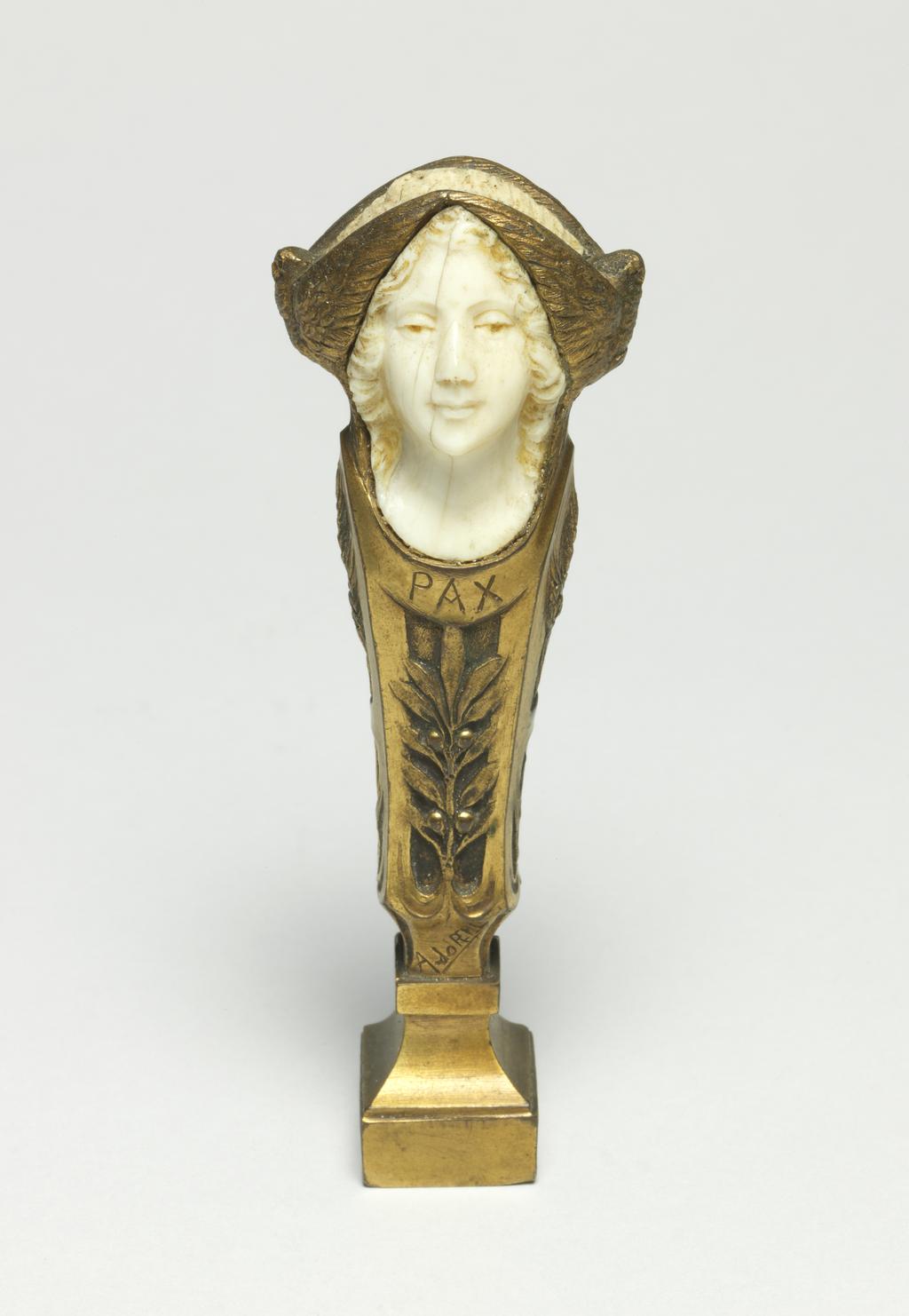 An image of Seal Fob. Brass, with carved ivory or bone female head. Inscriibed 'PAX', initial on base. French.