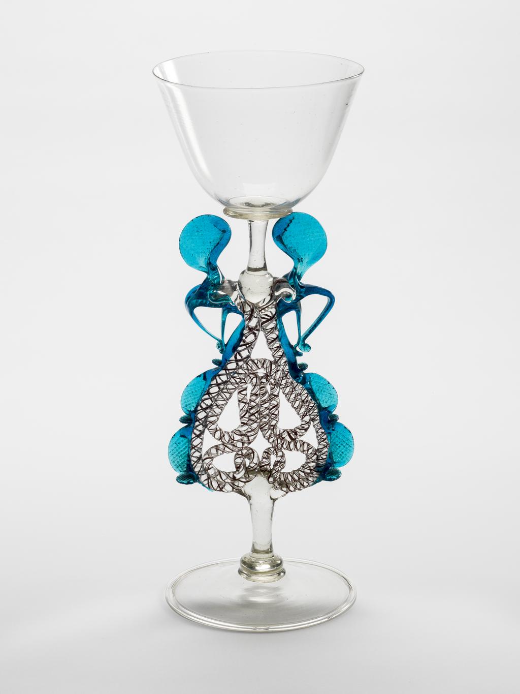 An image of Drinking Glasses/Wine Glass. Unknown Maker, either Germany (Cassel) or The Netherlands. Clear glass (cristallo) with cup bowl supported on a stem composed of pincered blue wings attached to a twisted rod encasing red and white threads; folded foot. Clear glass, blown bowl, height, whole, 27 cm, diameter, whole, 10.1 cm, circa 1575-1625.