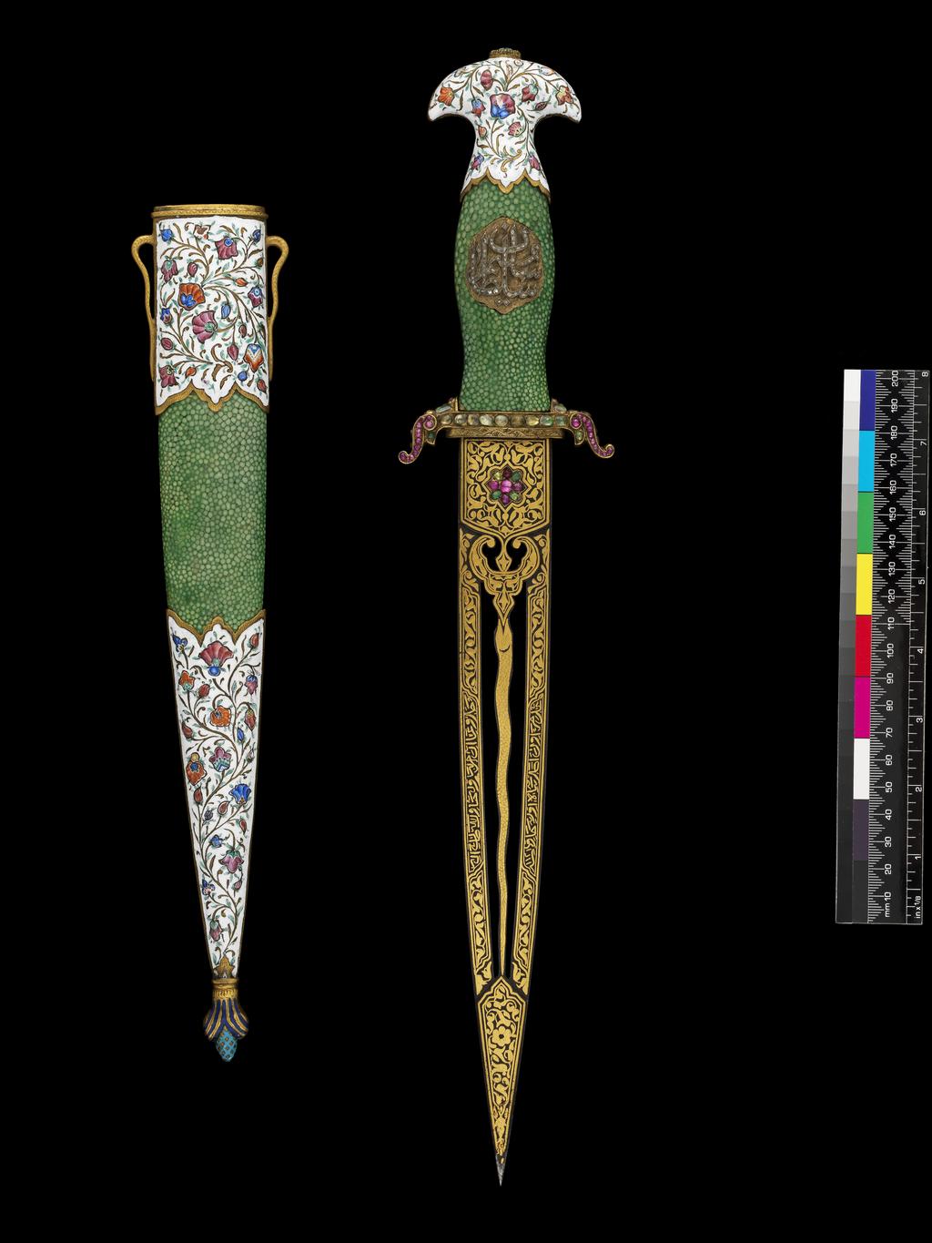 An image of Dagger and Scabbard (khanjar). The blade is straight and double edged, fretted with two slots at either side of a medial serpent, and around a lotus bud. The blade is set with four emeralds and five rubies at either side of the forte, and decorated overall with floral panels and inscriptions in thick gold koftgari. The blade bears the date 'sanat 1121'. The hilt comprises a bulbous grip in shagreen, with a medallion of small diamonds in a gilt setting at the centre reading ‘Sultan Sa’id’. The guard has small forward curved quillons set with various stones and gilded, and a pommel beaked at either side, enamelled in blue, red, pink and yellow in a white ground. The scabbard is of wood covered with shagreen, with large top locket and chape decorated in the same enamel, the chape with a large finial gilt with dark blue and turquoise enamel. Length (whole) 410 mm, width (blade) 270 mm, scabbard 310 mm, weight 280g. Blade 18th Century (1709-10), Turkish hilt & scabbard 19th Century. Turkish, Persian.