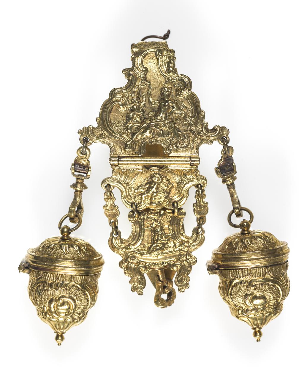 An image of Objets de vertu. Chatelaine with etui and two thimble cases. The chatelaine comprises three hinged sections the uppermost with a long spatulate hook; suspended from the top section are two thimble cases (A & B) with hinged lids; suspended from the centre of the lowest section is a shaped triangular etui (C) oval in section, with hinged lid and sprung button clasp. The fitted interior contains a folding knife (D) and a pair of ivory memorandum leaves hinged with a gilt button (E). (There are cavities for four more tools, which are missing). The cast chatelaine and embossed etui are chased with Classical figures and cherubs within borders of rococo scrolls and rocaille decoration. The two thimble holders are similarly decorated. Gilt metal, cast, embossed and chased, length, whole, 20.0 cm, height, etui, 1.9 cm, length, etui, 10.5 cm, width, etui, 4.0 cm, height, thimblecase, 2.2 cm, length, thimblecase, 3.9 cm, width, thimblecase, 2.7 cm, circa 1760. Rococo.