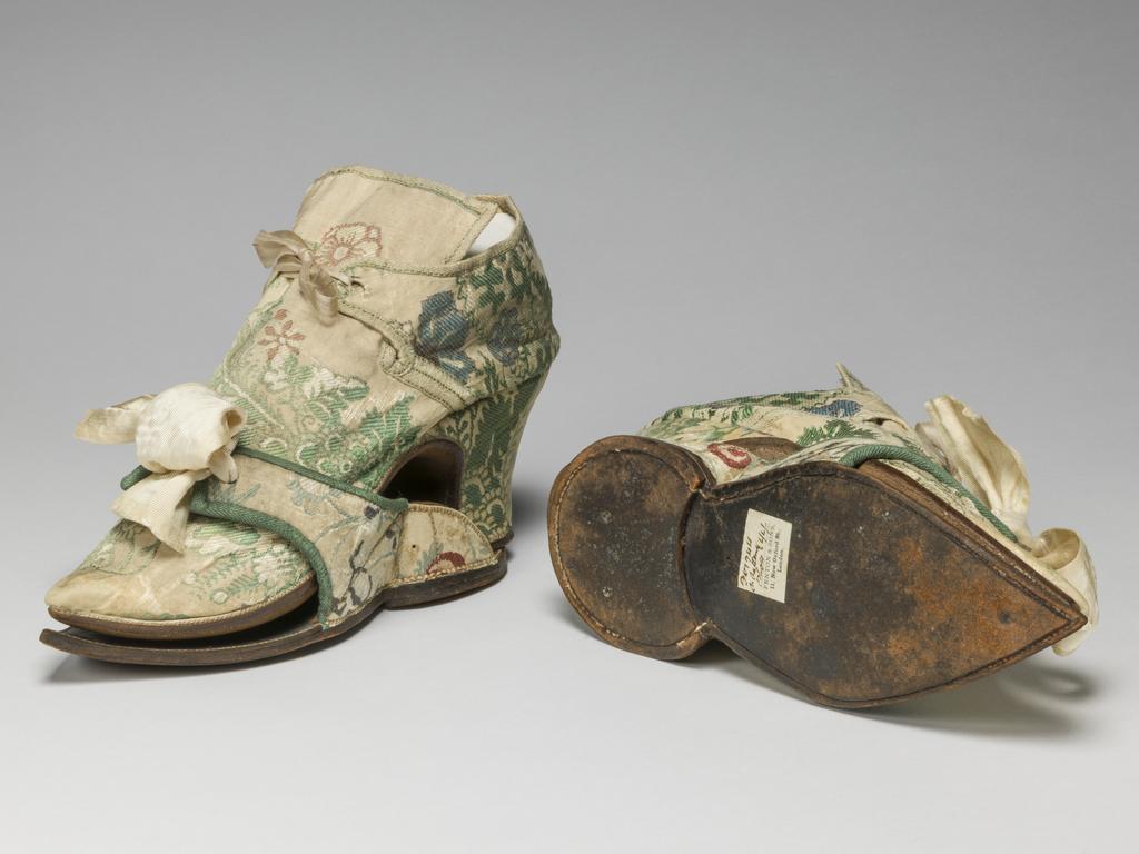 An image of Textiles/Shoes and pattens. Brocaded silk, cream background, multicoloured floral design. Shoes lined with coarse linen, tongues with green sarcenet, bound green braid. Pattens lined scarlet flannel, bound green braid, cream corded silk bows, leather soles and heels. Length, whole, 8.25 in, circa 1700-1749. English.