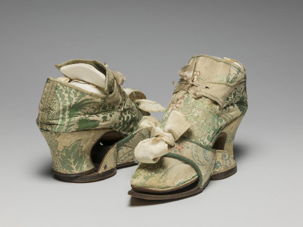 An image of Textiles/Shoes and pattens. Brocaded silk, cream background, multicoloured floral design. Shoes lined with coarse linen, tongues with green sarcenet, bound green braid. Pattens lined scarlet flannel, bound green braid, cream corded silk bows, leather soles and heels. Length, whole, 8.25 in, circa 1700-1749. English.