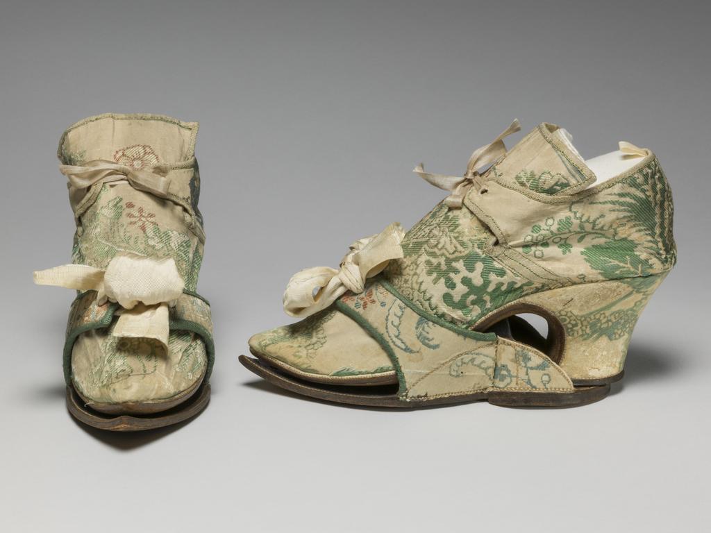 An image of Textiles/Shoes and pattens. Brocaded silk, cream background, multicoloured floral design. Shoes lined with coarse linen, tongues with green sarcenet, bound green braid. Pattens lined scarlet flannel, bound green braid, cream corded silk bows, leather soles and heels. Length, whole, 8.25 in, circa 1700-1749. English.