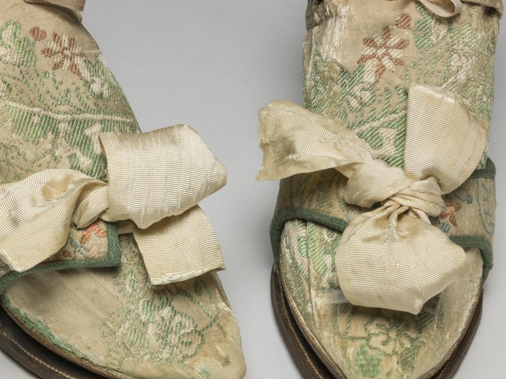 An image of Textiles/Shoes and pattens. Brocaded silk, cream background, multicoloured floral design. Shoes lined with coarse linen, tongues with green sarcenet, bound green braid. Pattens lined scarlet flannel, bound green braid, cream corded silk bows, leather soles and heels. Length, whole, 8.25 in, circa 1700-1749. English.
