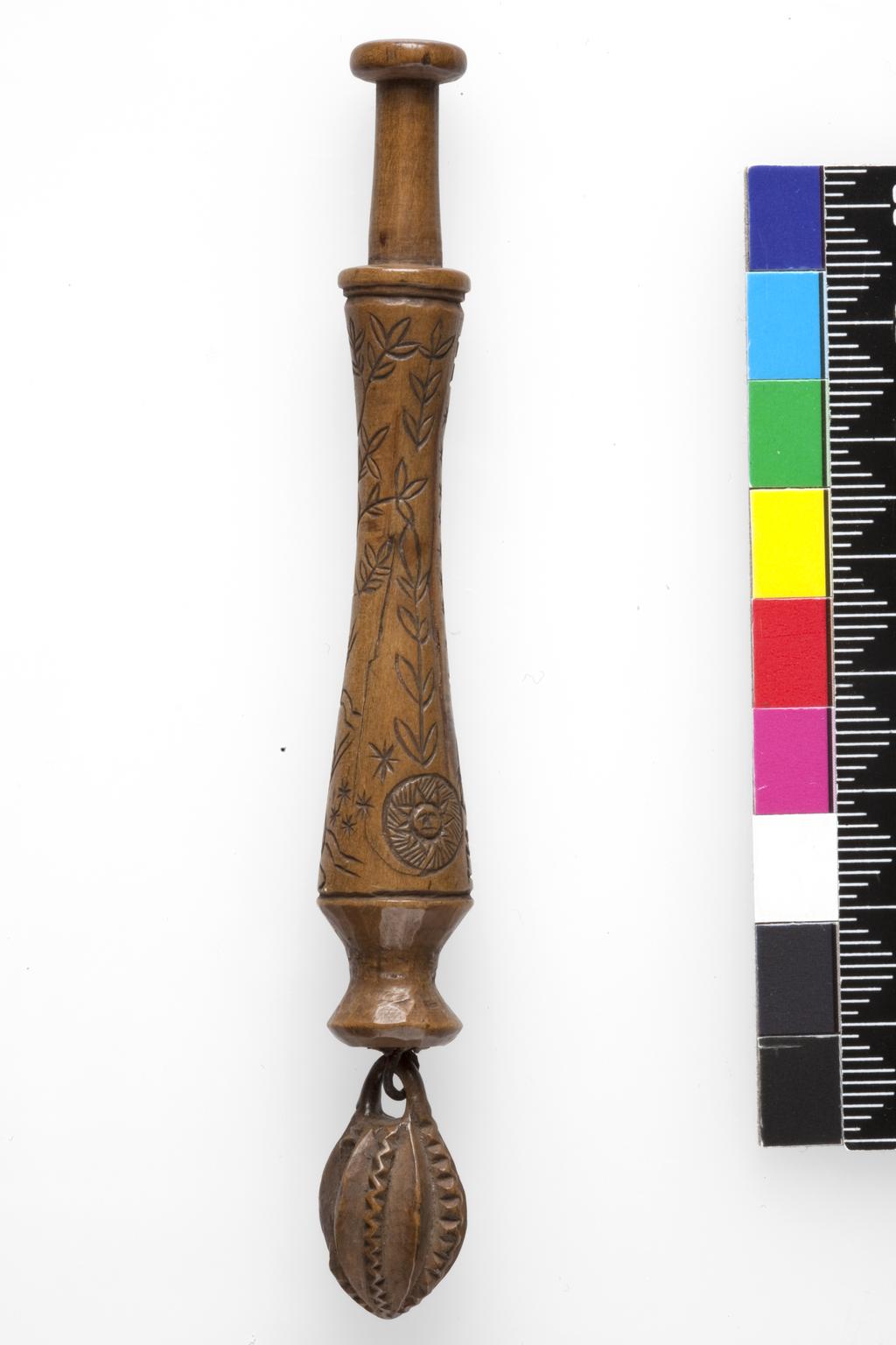 An image of Lace Bobbin. Unknown maker, Bedfordshire, Dunstable Downs. Wood, carved with figures (maker and his wife), sheep, (his) dog, bushes and the sun, moon and stars. Circa 1795. No dimensions.