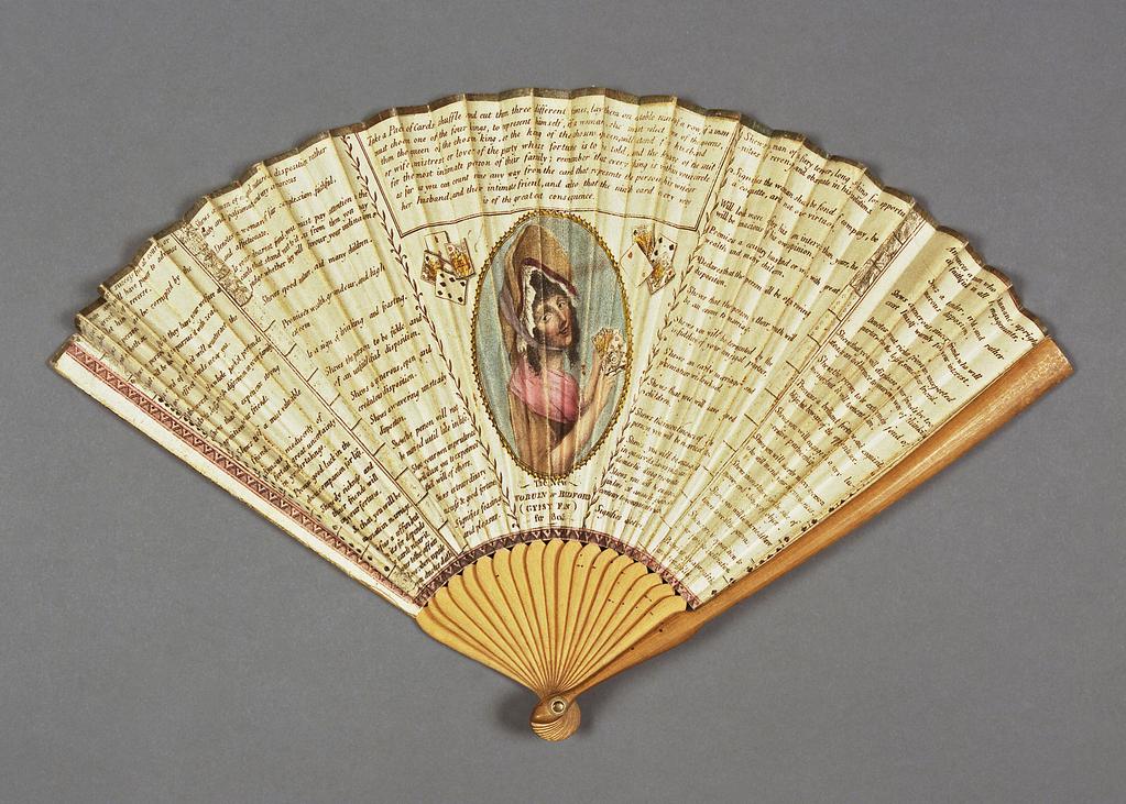 An image of Folding fan. New Woburn or Bedford Gypsy Fan for 1805. Unknown maker, England. Front: The leaf is divided into five vertical panels. In the central panel, flanked by groups of 4 cards, there is an oval coloured print of a gypsy wearing a bonnet and holding a pack of cards, with below 'The New/WOBURN or BEDFORD/(GYPSY FAN)/for 1805', and above instructions for fortune telling. Running down the left side of the two panels on the left and the right of the two panels on the right are the suits of cards with the Kings at the top. Beside each card there is a statement about the character or future of the chooser of that card. The left, lower and right edges have borders of black zigzag painted pink. Reverse: Undecorated. Double paper leaf printed in black and painted in water-colours. Gold paper binding on upper edge. Sticks and guards of wood (18+2). Brass ? rivet with bone or ivory washer. Length, guards, 18.8 cm, 1805.
