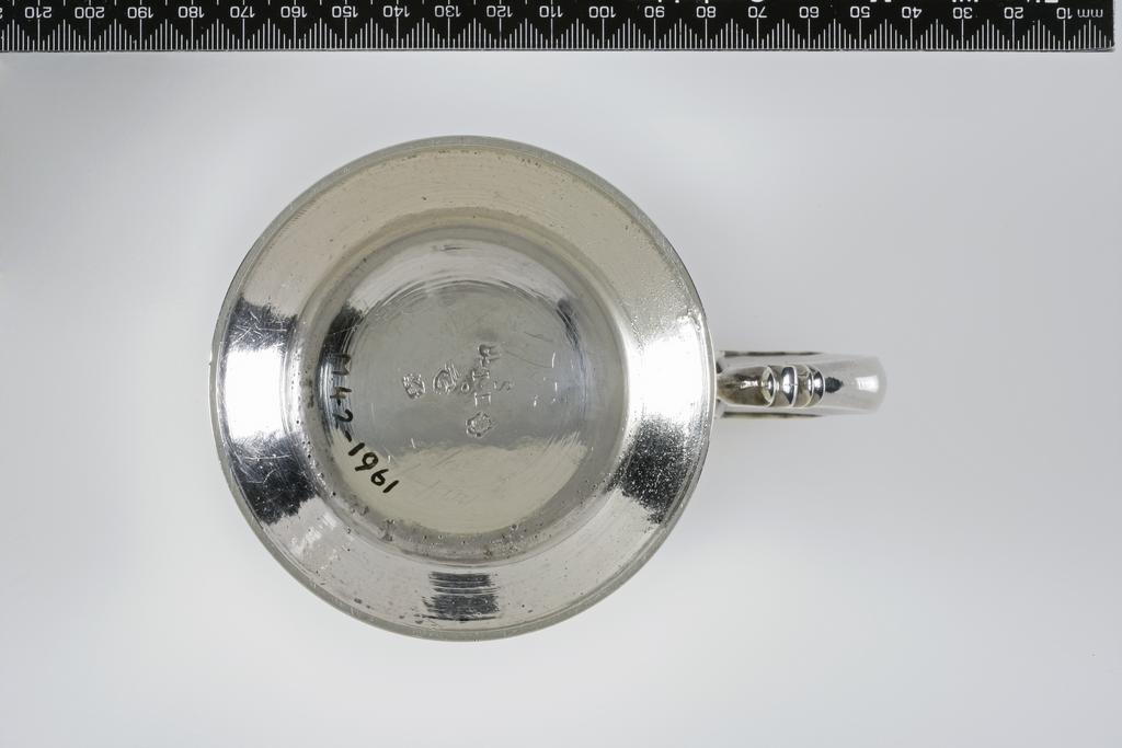An image of Mug. Grundy, William, silversmith, London. Plain baluster body on a circular moulded foot with cast, leaf-capped hollow handle. The interior gilt; engraved on the base 'S' over 'IE'. Silver, raised, cast and engraved initials, height, top of handle, 12.3 cm, width, handle to rim, 14 cm, weight, whole, 385 g, 1752-1753.