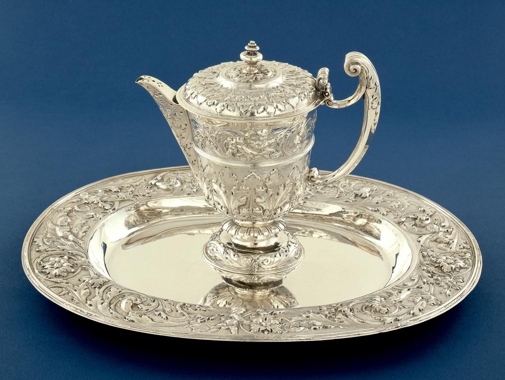 An image of Ewer and basin. Unknown (silversmith). Silver; embossed, chased and matted, and decorated with acanthus leaves and putti amid scrolling foliage. Helmet-shaped ewer on a short stem and oval foot, with projecting covered spout, the cover perforated at the end; cast harp-shaped handle; and covex cover with a raised circle in the centre and a cast 'turned' finial. The body of is decorated below the rim with a frieze of putti amid scrolling foliage separated by a filet from a calyx of acanthus leaves growing upwards from the junction with the stem which has a gadrooned 'frill' half way up. The spout is wrapped in acanthus foliage, and there is a leaf extending downwards from the top of the handle. The foot has a border of scrolling foliage, and the cover has acanthus foliage radiating from the raised centre. (A) Oval basin with applied reeded edge, wide rim, and shallow oval well. It has a plain centre, and on the rim, four putti amid scrolling foliage with a matted ground. The putti among foliage may have been derived from engraved designs by Jean Lepautre (1618-82). The ewer and basin are unmarked but are most likely to have been made in Paris. Height (ewer - to finial top) 21 cm, weight (ewer - whole) 880 g, length (basin) 41.5 cm, width (basin) 30.2 cm, weight (basin - whole) 923 g, circa 1656 to 1660.