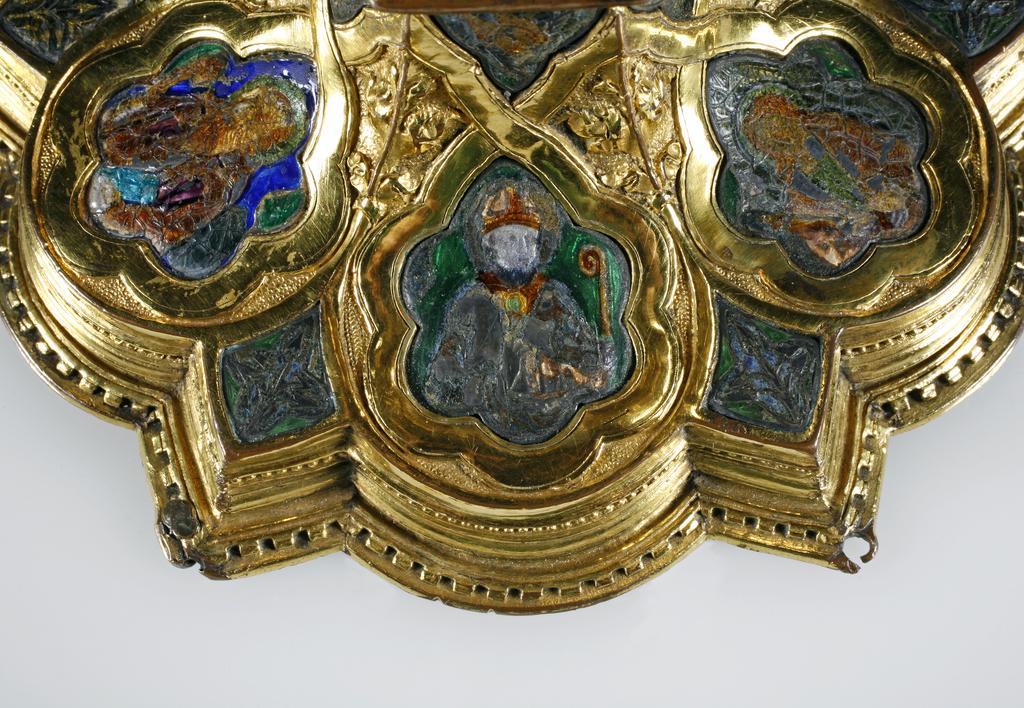 An image of Silver/Church Plate. Chalice. Petruccio Campagnini, Andrea, probably (active Tuscany, Siena, Italy). Set with six silver medallions of Christ, St Peter, St. Paul, St. John, St. Bartholomew and possibly St. Barnabus. Above the knop the stem is engraved with six male busts without nimbi; below the knop the stem is engraved with six birds. At the base of the stem are moulded borders containing a plain band engraved and enamelled with the inscription 'ANDREA * PETRUCI * DE * SENIS * ME *FECI(T). The low copper-gilt trumpet-shaped foot has a shaped circular spreading base with rim of twelve alternating semicicular and pointed lobes. It is set with six applied silver plaques with translucent enamels on sunk relief, representing the Crucifixion with Instruments of the Passion, on either side of which are the Virgin and St. John; on the opposite side are a bishop with mitre and crozier between a male and female saint. Above are smaller shaped triangular plaques enamelled with the heads of angels; and below are lozenge shaped plaques enamelled with a stylised leaf. The base stands on a foot ring decorated with moulded, beaded and dentil borders. Bowl silver-gilt with silver calyx, foot and stem of copper-gilt, decorated with embossing and chasing, and set with silver plaques with basse taille enamelling, height, overall, 19 cm, diameter, base, 12.8 cm, maximum, diameter, rim, 9.9 cm, circa 1370. Late Medieval. Gothic.