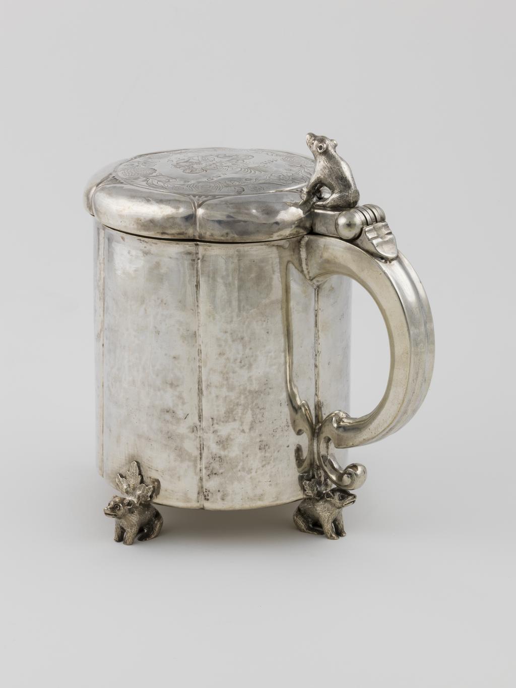 An image of Peg Tankard/Marriage Tankard. Enevoldsen, Neils (active 1648-1661, Danish). Silver, raising, embossing, seaming, casting, engraving, height, to top of finial, 22.2 cm, diameter, base, 14.7 cm, weight, whole, 1364 g, 1648. Slightly fluted cylindrical sides standing on four bear-shaped feet, the low cover engraved with armorials and with a bear-shaped thumb-piece. Baroque.