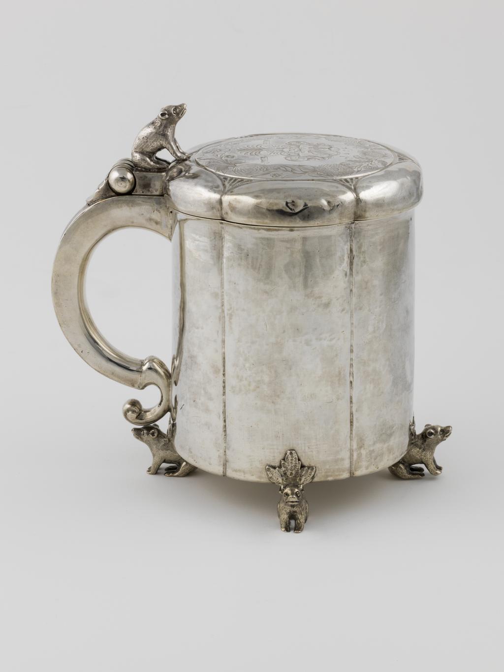 An image of Peg Tankard/Marriage Tankard. Enevoldsen, Neils (active 1648-1661, Danish). Silver, raising, embossing, seaming, casting, engraving, height, to top of finial, 22.2 cm, diameter, base, 14.7 cm, weight, whole, 1364 g, 1648. Slightly fluted cylindrical sides standing on four bear-shaped feet, the low cover engraved with armorials and with a bear-shaped thumb-piece. Baroque.