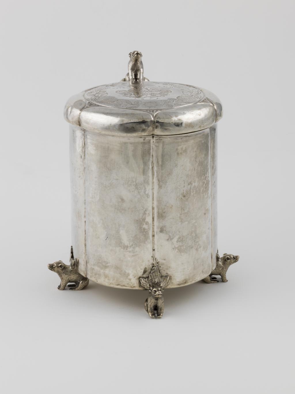 An image of Peg Tankard/Marriage Tankard. Enevoldsen, Neils (active 1648-1661, Danish). Silver, raising, embossing, seaming, casting, engraving, height, to top of finial, 22.2 cm, diameter, base, 14.7 cm, weight, whole, 1364 g, 1648. Slightly fluted cylindrical sides standing on four bear-shaped feet, the low cover engraved with armorials and with a bear-shaped thumb-piece. Baroque.