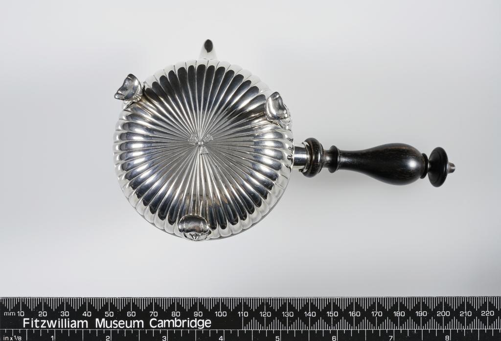 An image of Chocolate Pot/Teapot/Hot Milk Jug. Delapierre, Michel II (French, Paris, master 1737, recorded 1785). Half fluted almost spherical body with wood handle. The short beak-like spout has a heart-shaped opening. The hinged cover is flat and gadrooned, and has a acorn-shaped finial. The jug stands on three scroll legs with fleur-de lis, scroll and flower capitals. Opposite the handle is engraved a coat-of-arms. Silver body, raised, embossed and matting with engraved armorials, cast finial and legs, wooden handle, height, to top of finial, 9.4 cm, width, side to handle, 15.8 cm, weight, gross, 190 g, 1758-1759. Louis XV.