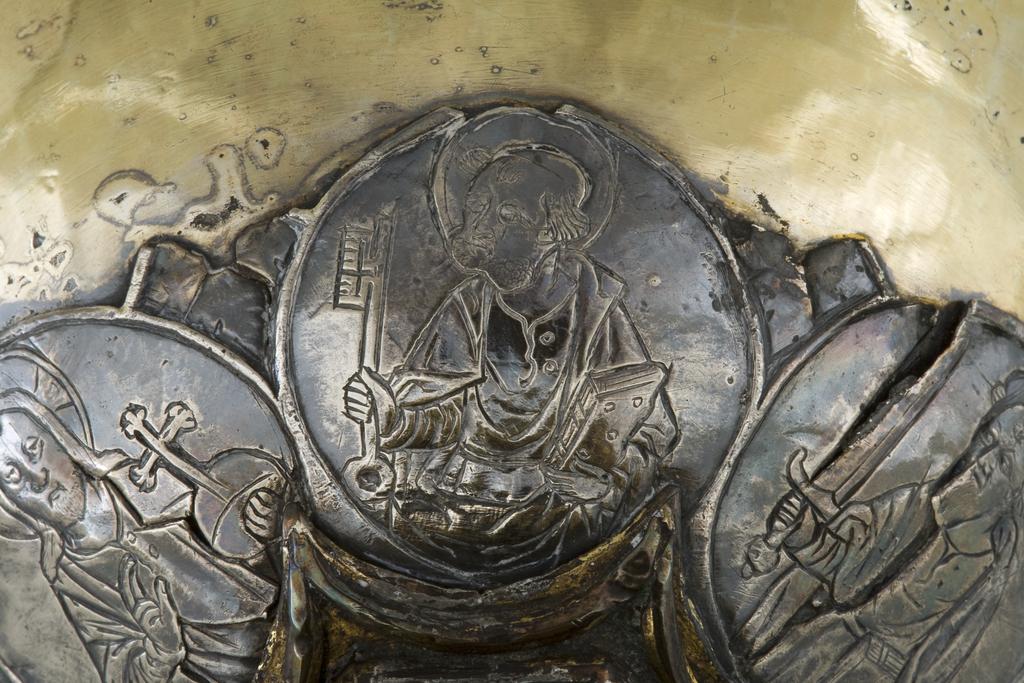 An image of Silver/Church Plate. Chalice. Petruccio Campagnini, Andrea, probably (active Tuscany, Siena, Italy). Set with six silver medallions of Christ, St Peter, St. Paul, St. John, St. Bartholomew and possibly St. Barnabus. Above the knop the stem is engraved with six male busts without nimbi; below the knop the stem is engraved with six birds. At the base of the stem are moulded borders containing a plain band engraved and enamelled with the inscription 'ANDREA * PETRUCI * DE * SENIS * ME *FECI(T). The low copper-gilt trumpet-shaped foot has a shaped circular spreading base with rim of twelve alternating semicicular and pointed lobes. It is set with six applied silver plaques with translucent enamels on sunk relief, representing the Crucifixion with Instruments of the Passion, on either side of which are the Virgin and St. John; on the opposite side are a bishop with mitre and crozier between a male and female saint. Above are smaller shaped triangular plaques enamelled with the heads of angels; and below are lozenge shaped plaques enamelled with a stylised leaf. The base stands on a foot ring decorated with moulded, beaded and dentil borders. Bowl silver-gilt with silver calyx, foot and stem of copper-gilt, decorated with embossing and chasing, and set with silver plaques with basse taille enamelling, height, overall, 19 cm, diameter, base, 12.8 cm, maximum, diameter, rim, 9.9 cm, circa 1370. Late Medieval. Gothic.
