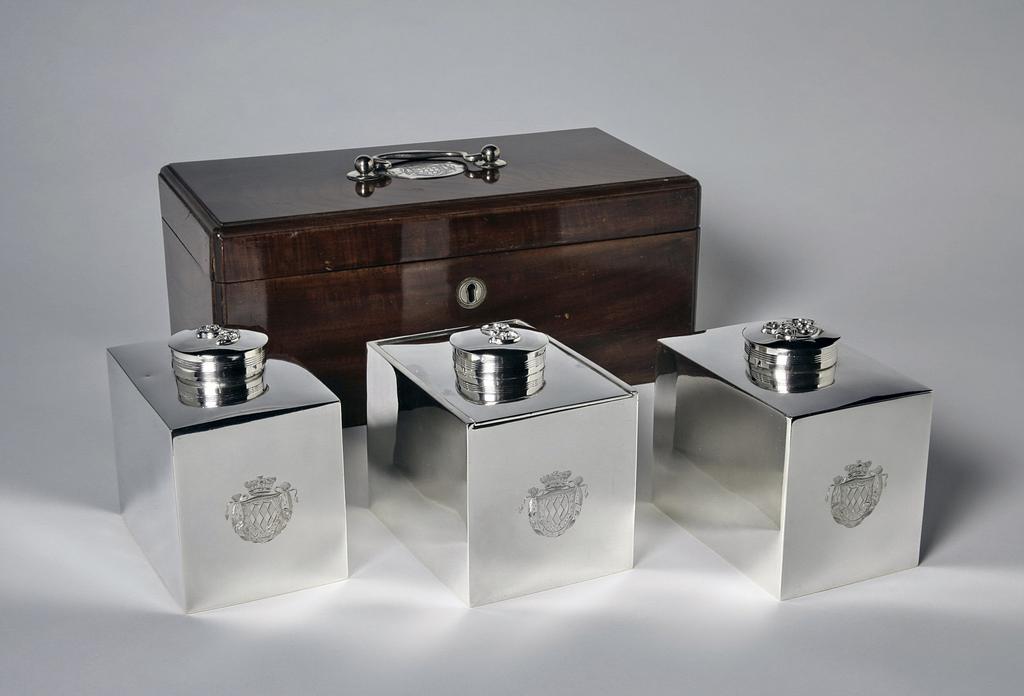 An image of M.7.1 & A-1965, M.7.2 & A & B-1965 and M.7.3 & A-1965. A cased set of two tea caddies and a sugar box. Thompson, William II, silversmith, probably (English). Production Place: England. The rectangular box with silver handle and oval mount engraved with the coat of arms of Richard, 7th Viscount Fitzwilliam. Mahogany case with silver handles and mounts, height, overall, 14 cm, length, overall, 32.4 cm, width, overall, 16.5 cm, 1812-1813.
