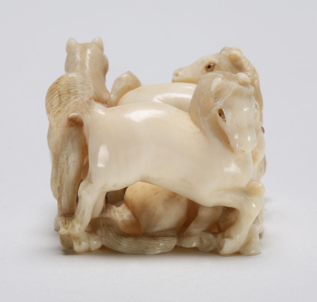 An image of Netsuke: katabori: Group of five horses. Shigehiro, Osaka School, Japan. Five horses arranged to form a rectangular group, three standing and two reclining, each with inlaid eyes. The legs and tails are entwined creating a latticework effect on the underside. The manes and tails are finely carved. Natural himotoshi are formed by the legs and tails. Ivory, carved and polished, height 2.5 cm, width 4.4 cm, circa 1868-1900. Edo Period (1615-1868). Collection: H.S. Reitlinger. Notes: The Horse (uma) is seen by the Japanese as an emblem of virility and endurance.