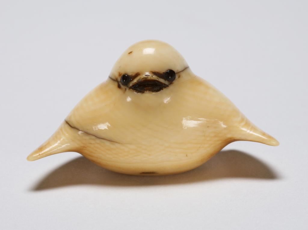 An image of Netsuke; katabori. Bird. Tamakazu, Edo Period (1603-1868), Japan. Small, squat bird with open beak, the rounded body flanked by short outspread wings and erect tail. Eyes black, inlaid in horn. Very smooth, no incised details but slight staining. Himotoshi on the underside. Ivory, carved, eyes inlaid in horn, height, whole, 2.2 cm, width, whole, 4.3 cm, circa 1800-1868. Collection: H.S. Reitlinger.