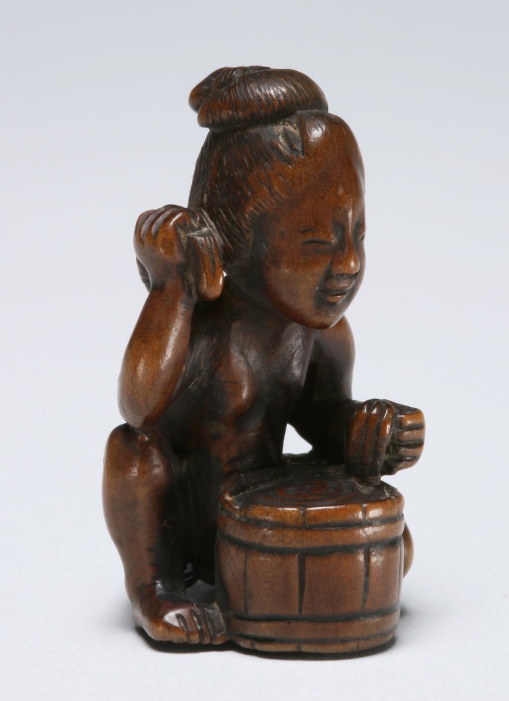 An image of Netsuke. A naked woman crouched at a tub, washing her back. Unknown maker, Japan. Inscription: signature inlaid with mother of pearl; illegible. Wood, mother-of-pearl, height 4.5 cm. Acquisition Credit: Marlay Bequest.