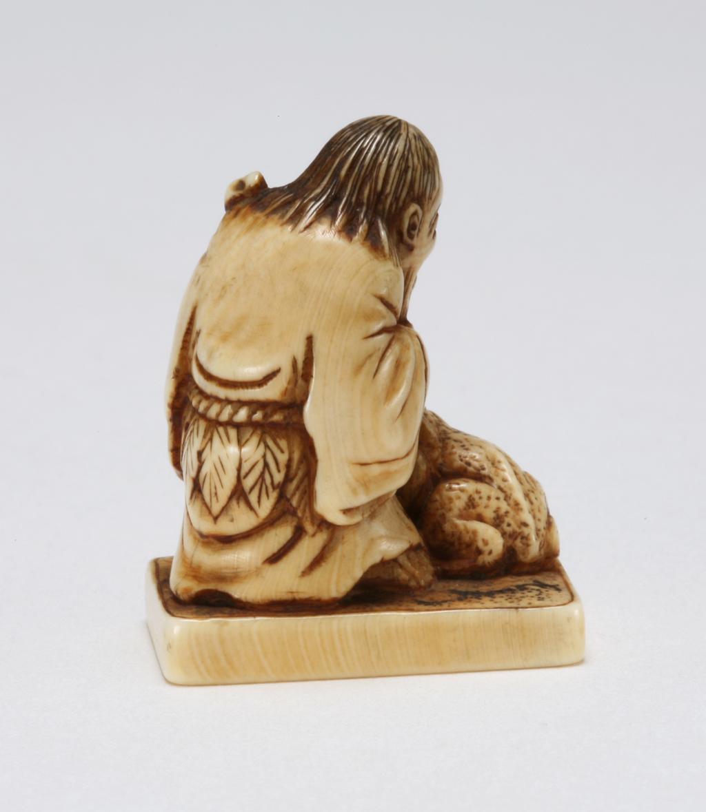 An image of Netsuke. Gama Sennin with his toad and stick. Unknown maker, Japan. Ivory, carved and stained, height 3 cm. Acquisition Credit: Marlay Bequest.
