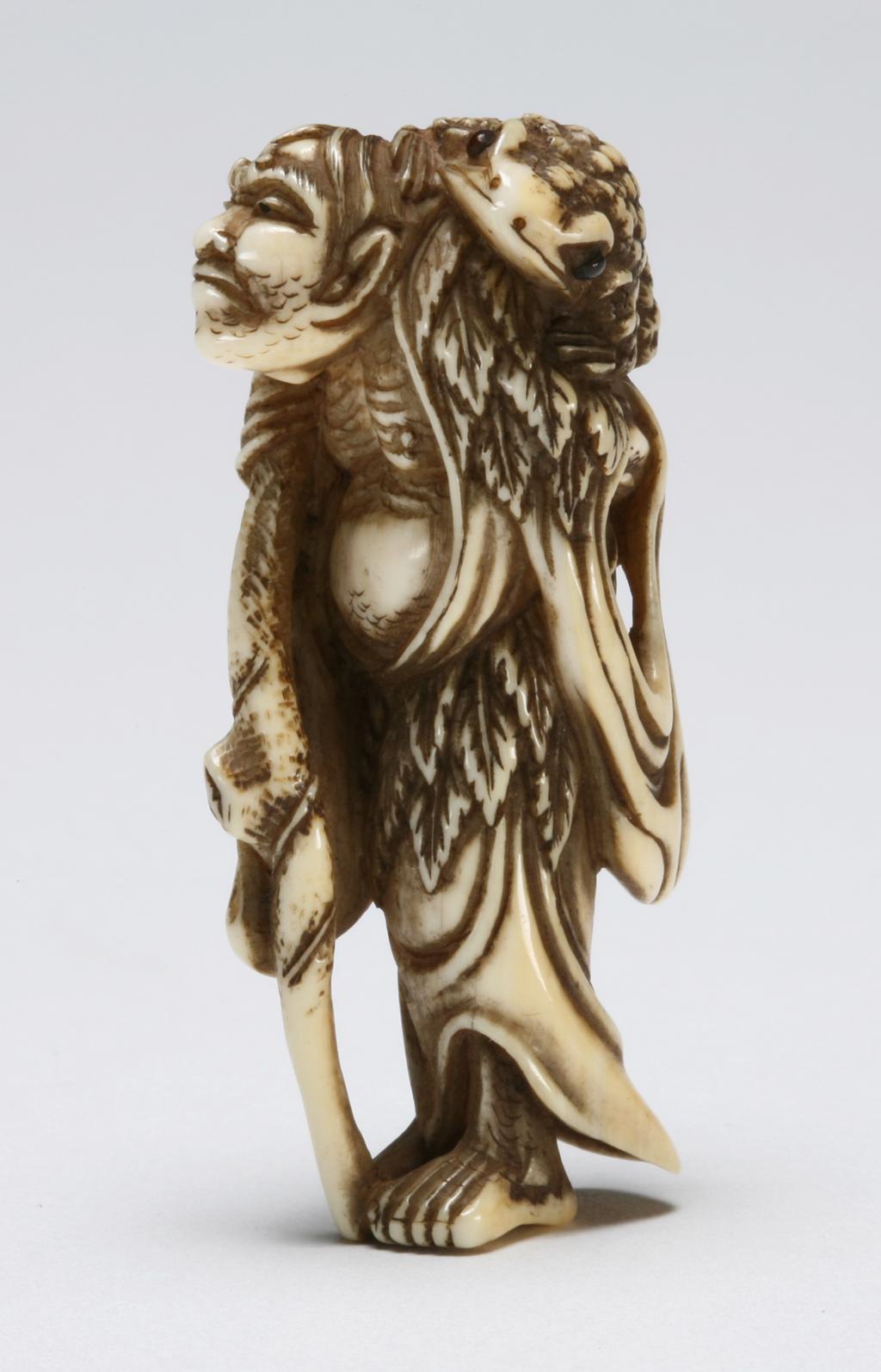 An image of Netsuke. Gama Sennin with his stick in his right hand and his toad on his left shoulder. Unknown maker, Japan. Ivory, carved and stained, height 5.5 cm. Acquisition Credit: Marlay Bequest.